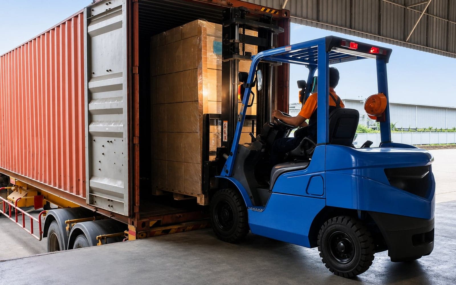 Forklift loading a shipping container inside a warehouse during a transload
